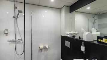 A modern bathroom with a glass shower enclosure, a white sink, and a dark-colored vanity.