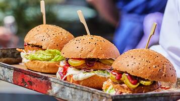 A tray with three burgers, each with a toothpick, on a metal tray.