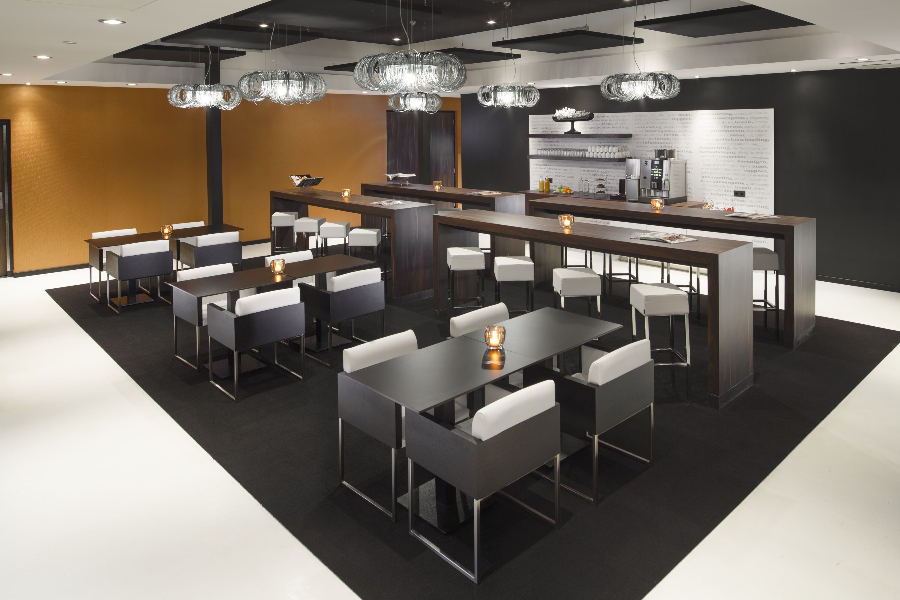 A modern dining area with multiple tables and chairs, a central bar area, and contemporary lighting fixtures.