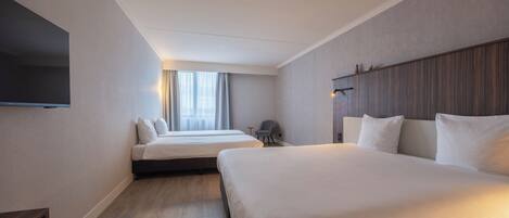 Habitación de hotel con dos camas, un televisor de pantalla plana montado en la pared, una mesita y una silla.