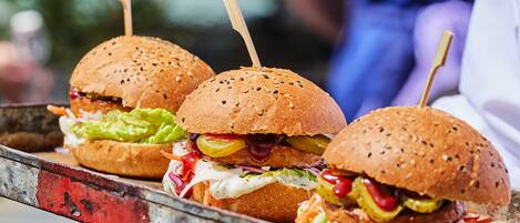 Una bandeja con tres hamburguesas, cada una con un palillo, sobre una bandeja metálica.