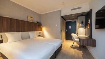 Una habitación de hotel moderna con una cama grande, un escritorio con espejo y una silla.