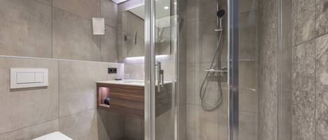 Un baño moderno con ducha de vidrio, inodoro y tocador con espejo.