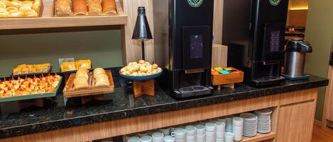Un bufé de desayuno con diferentes alimentos y máquinas de café.