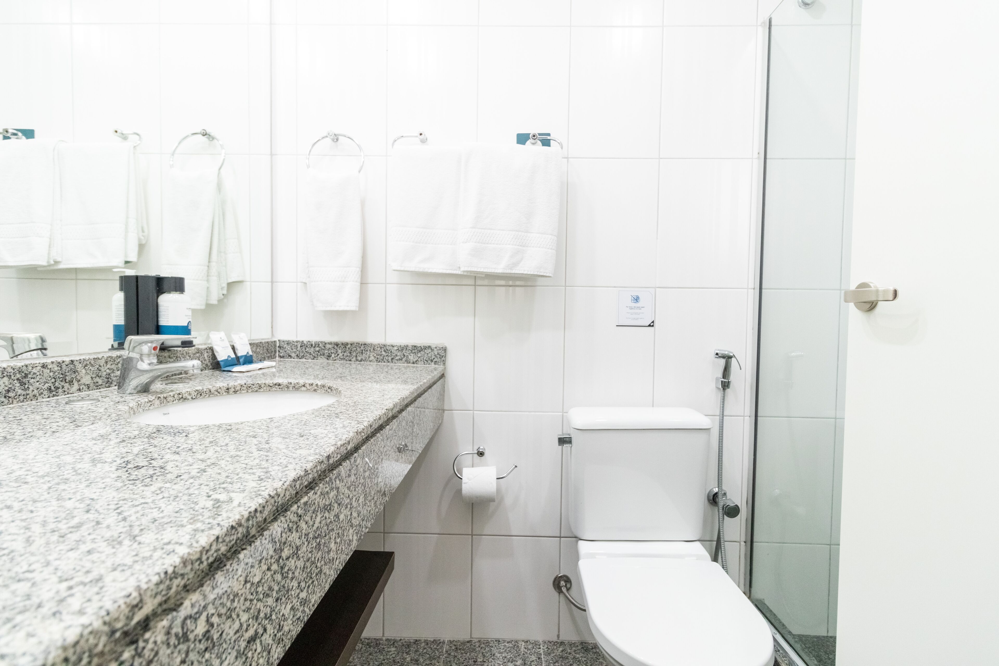A bathroom with two sinks, a toilet, and a glass shower stall.