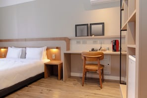 A hotel room with a bed, bedside table, desk, chair, and wall-mounted artwork. - SLAVIERO Curitiba Shopping (Curitiba)