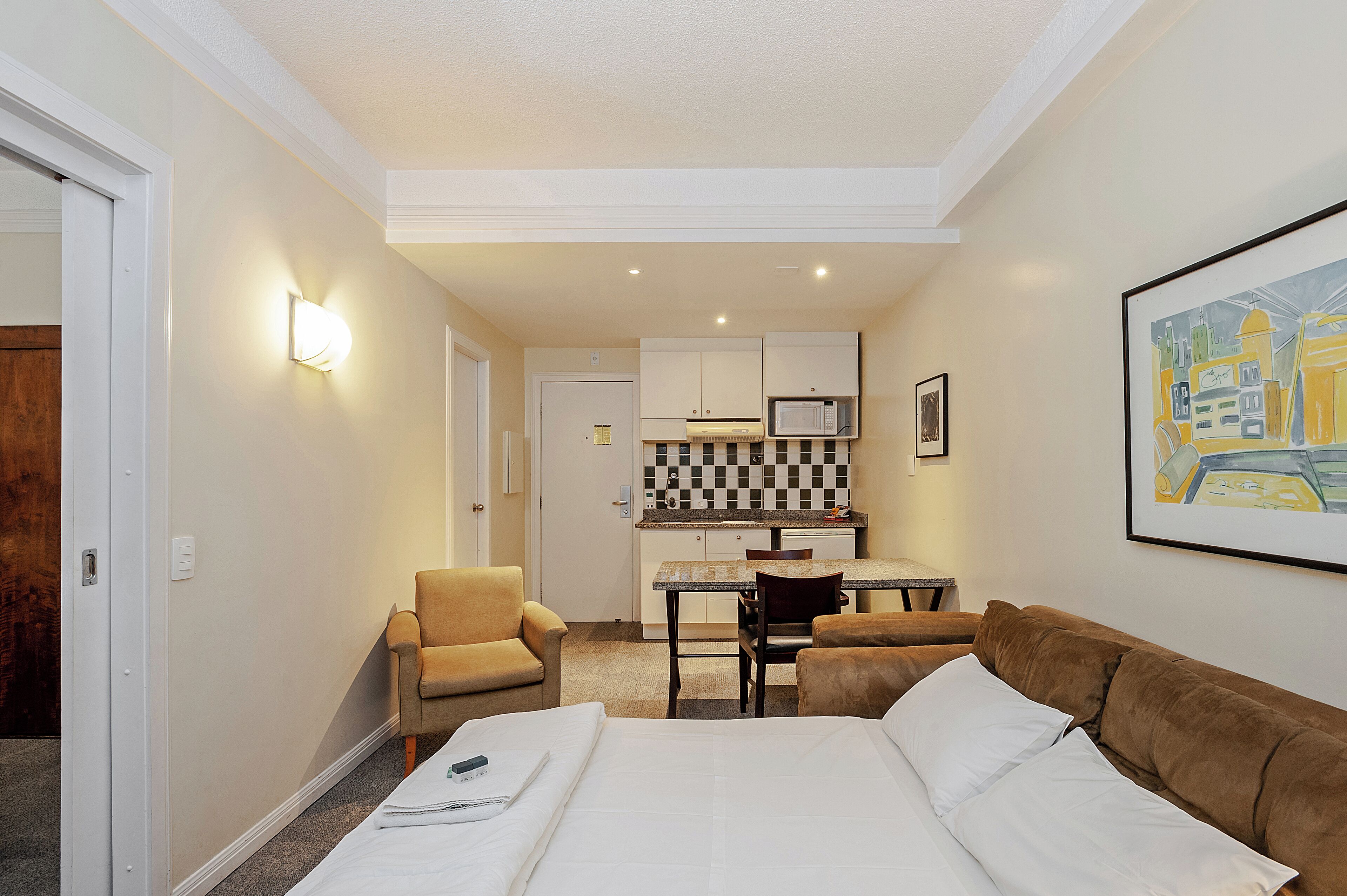 Ein Hotelzimmer mit einem Bett, einer Couch, einem Schreibtisch mit Stuhl und einer Küchenzeile.