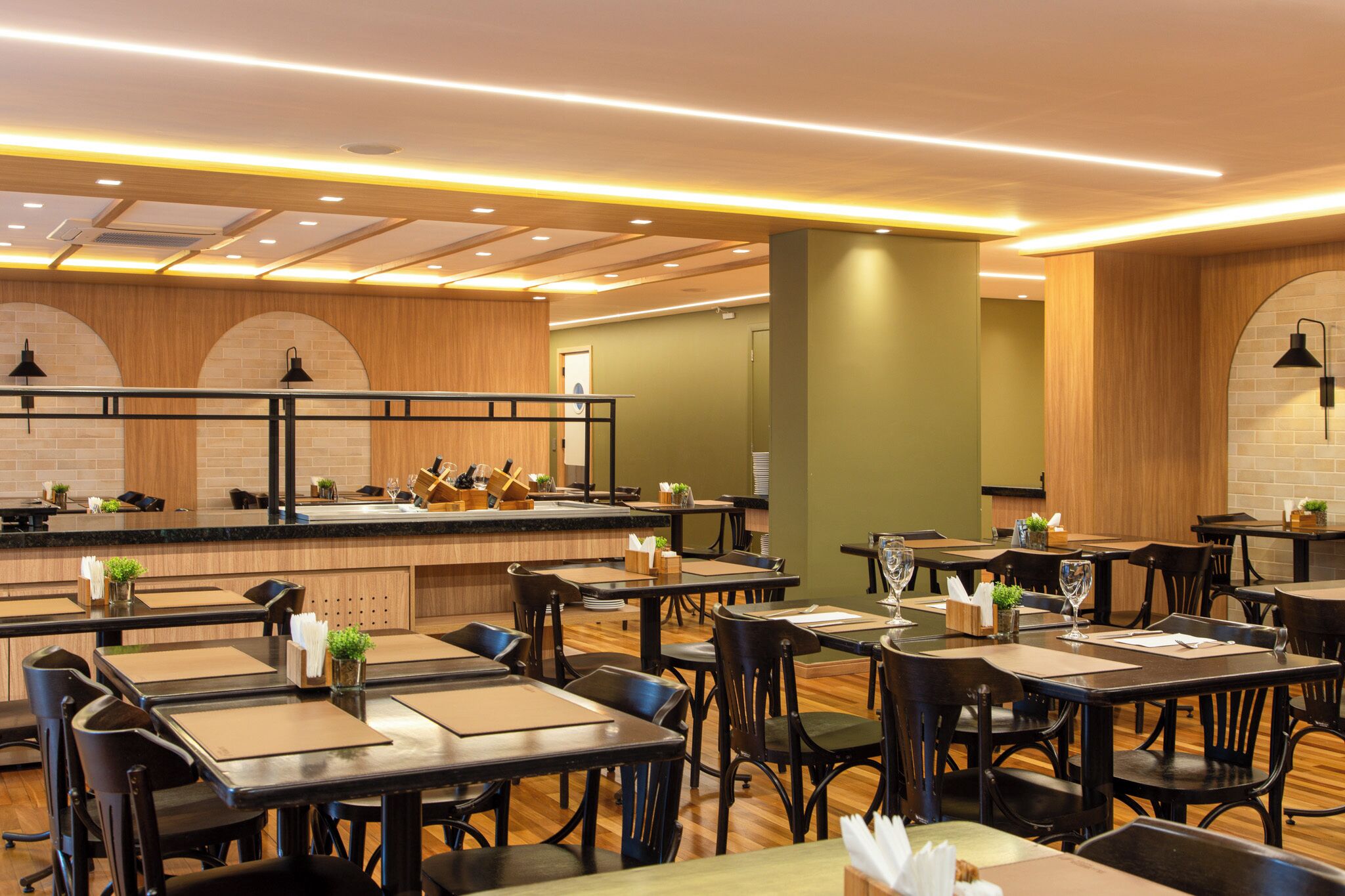 Ein Restaurant mit mehreren Tischen und Stühlen, einer Theke mit einer Vitrine und einem Holzbalken-Design an der Decke.
