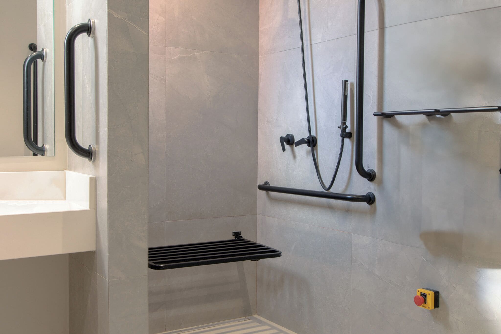 A shower area with a grab bar, a towel rack, and a control panel.