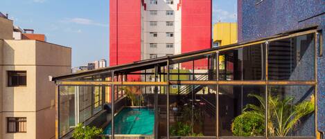 Un edificio moderno con una zona de piscina cubierta de cristal, rodeada de edificios coloridos.