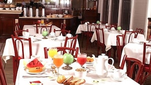 Un restaurant proposant plusieurs tables préparées pour le petit-déjeuner, avec un choix varié de plats et de boissons.
