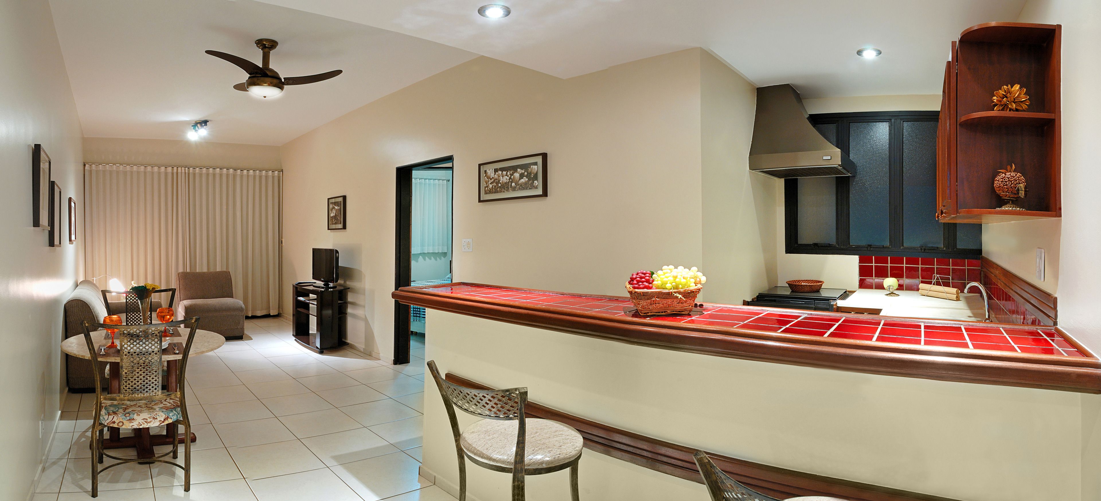 A modern kitchen with a central island, a dining area with a sofa and chairs, and a ceiling fan.