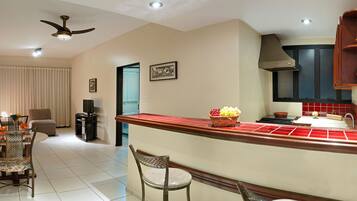 A modern kitchen with a central island, a dining area with a sofa and chairs, and a ceiling fan.
