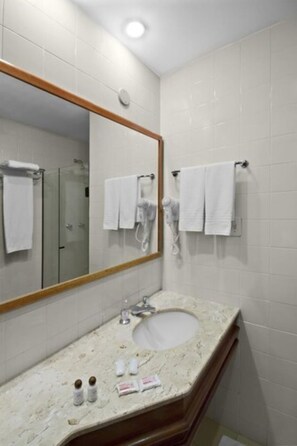 Een badkamer met een wastafel, spiegel en handdoekhouder.