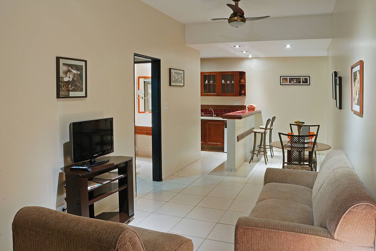 A living room with a TV, sofa, and dining area with chairs and a table.