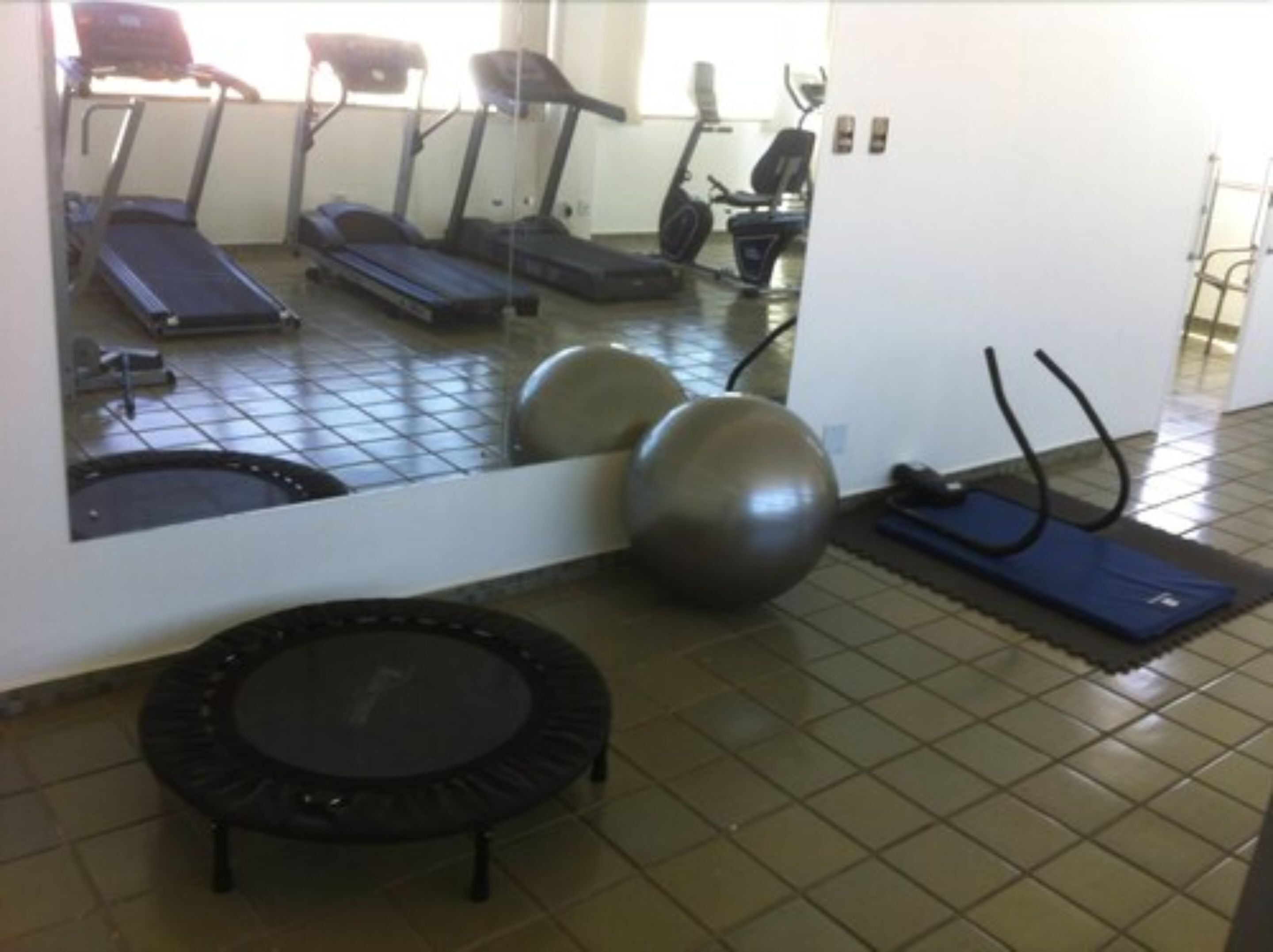 A gym with exercise equipment including treadmills, a trampoline, and exercise balls.