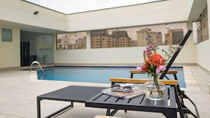 A poolside area with a lounge chair, a table with a vase of flowers, and a pair of sunglasses. - Matiz Manhattan (São Paulo)