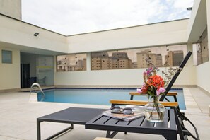 Una piscina al aire libre, sillones reclinables de piscina