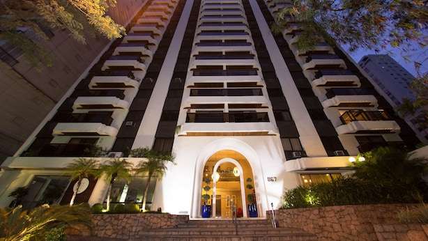 A tall hotel with a central arched entrance, multiple balconies, and a stone facade. - Matiz Manhattan (São Paulo)