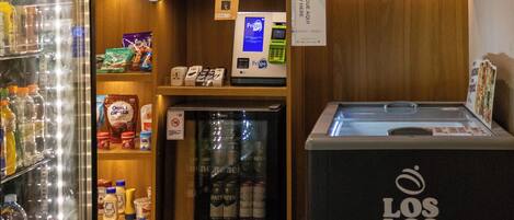 A mini-fridge with a 'Los Los' logo, a refrigerated section with beverages, and a 'Frigo' sign above a shelf with snacks.