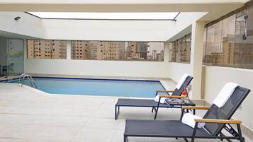 Una piscina al aire libre, sillones reclinables de piscina