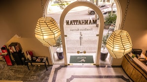 A hotel entrance with a reception desk, two hanging lamps, and a doormat with the hotel name. - Matiz Manhattan (São Paulo)