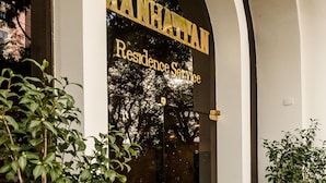 A hotel entrance with a glass door, a doormat, and two potted plants. - Matiz Manhattan (São Paulo)