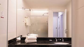 A modern bathroom with a black marble countertop, a white sink, and a glass shower enclosure.