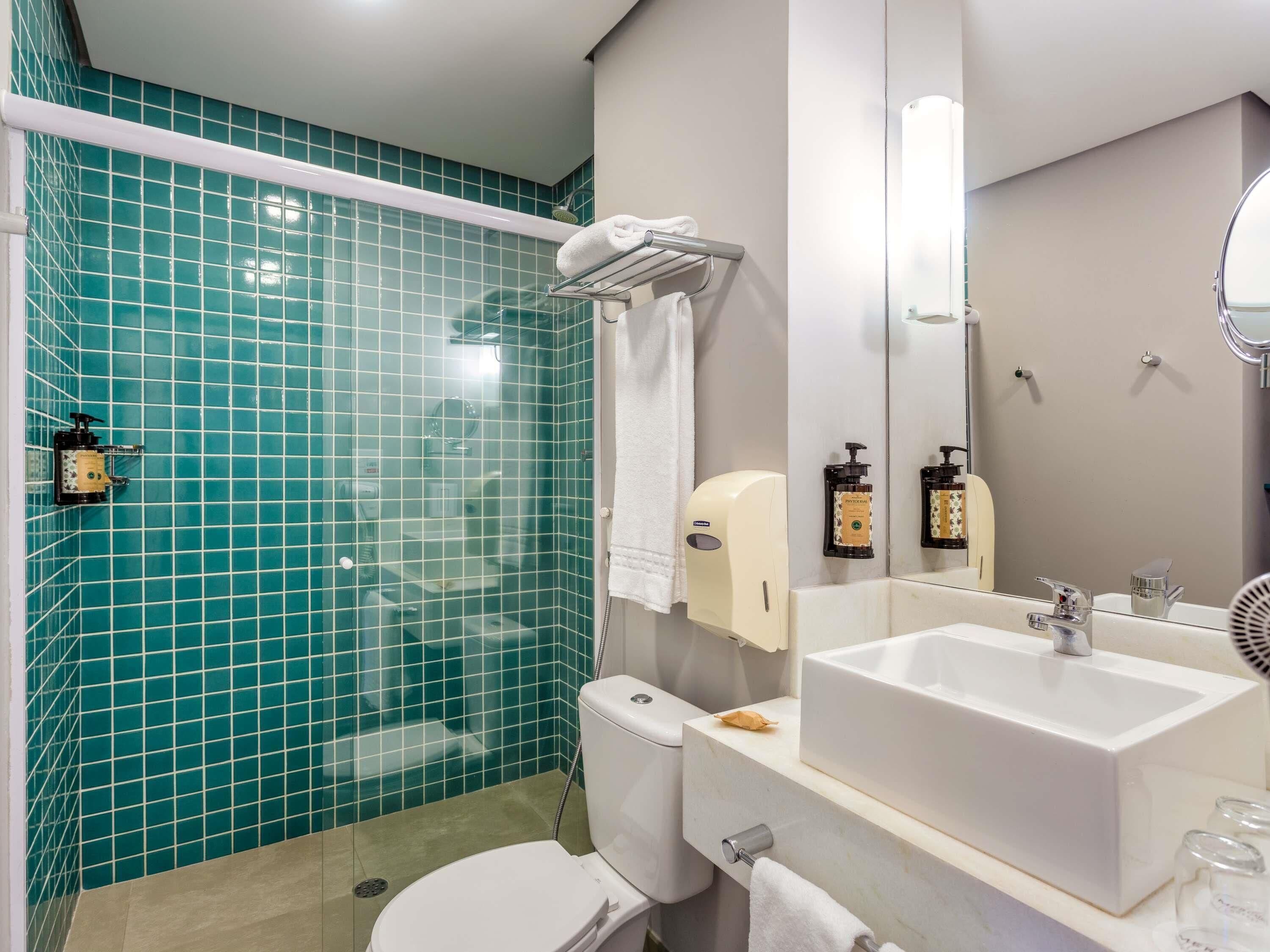 A bathroom with a shower, toilet, sink, and a mirror.
