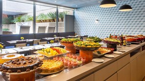 A buffet with various food items and a modern interior with patterned walls and pendant lighting. - Mercure São Paulo JK (São Paulo)