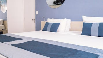 Una habitación de hotel con una cama, una mesita de noche, una lámpara y un espejo circular en la pared.