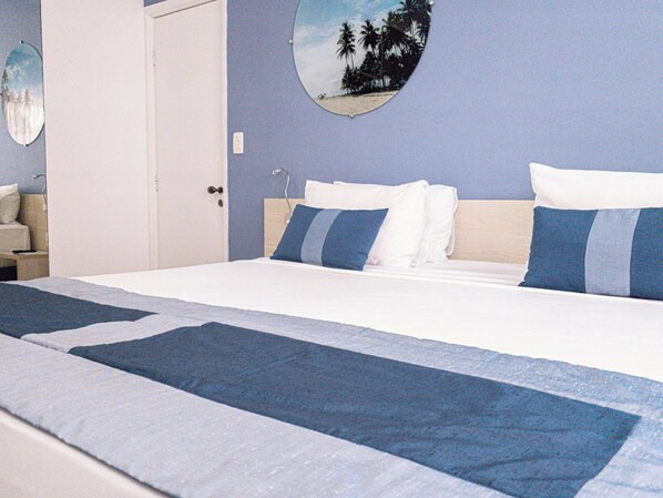 Una habitación de hotel con una cama, una mesita de noche, una lámpara y un espejo circular en la pared.