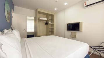 Una habitación de hotel con cama, armario, televisor y aire acondicionado.