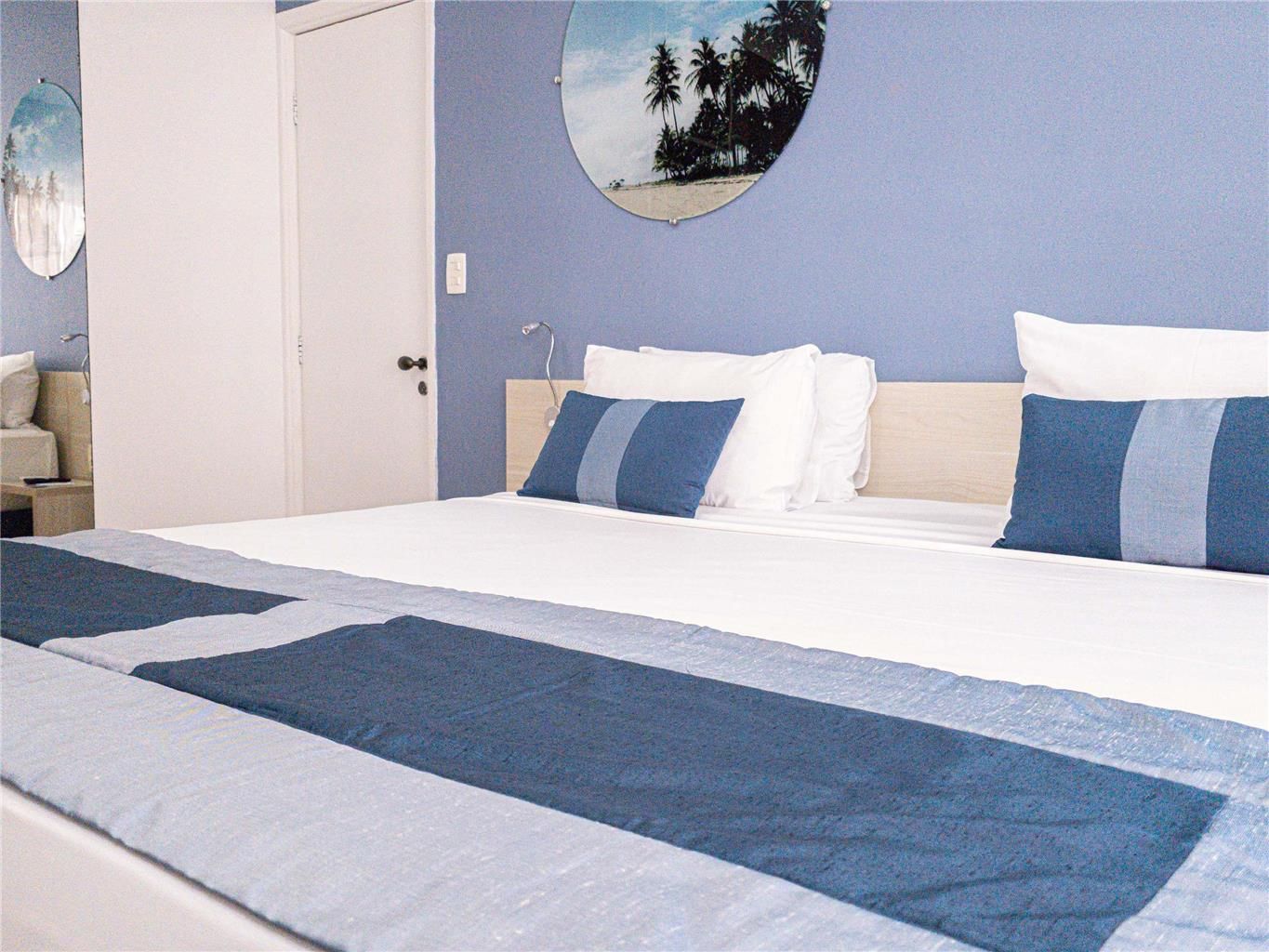 A hotel room with a bed, a round wall mirror, and a door.
