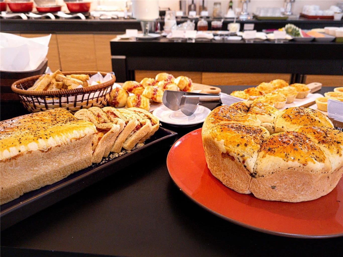 A buffet with various baked goods including bread and pastries.