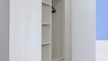 Un vestidor amplio con varios estantes y espacio para colgar, piso de madera y luces empotradas en el techo.