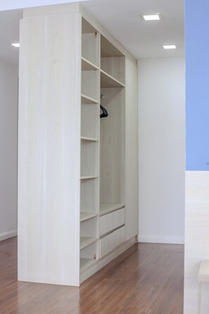 Un vestidor amplio con varios estantes y espacio para colgar, piso de madera y luces empotradas en el techo.