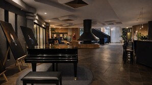 Un vestíbulo espacioso con un piano de cola, una escalera y una zona de bar.
