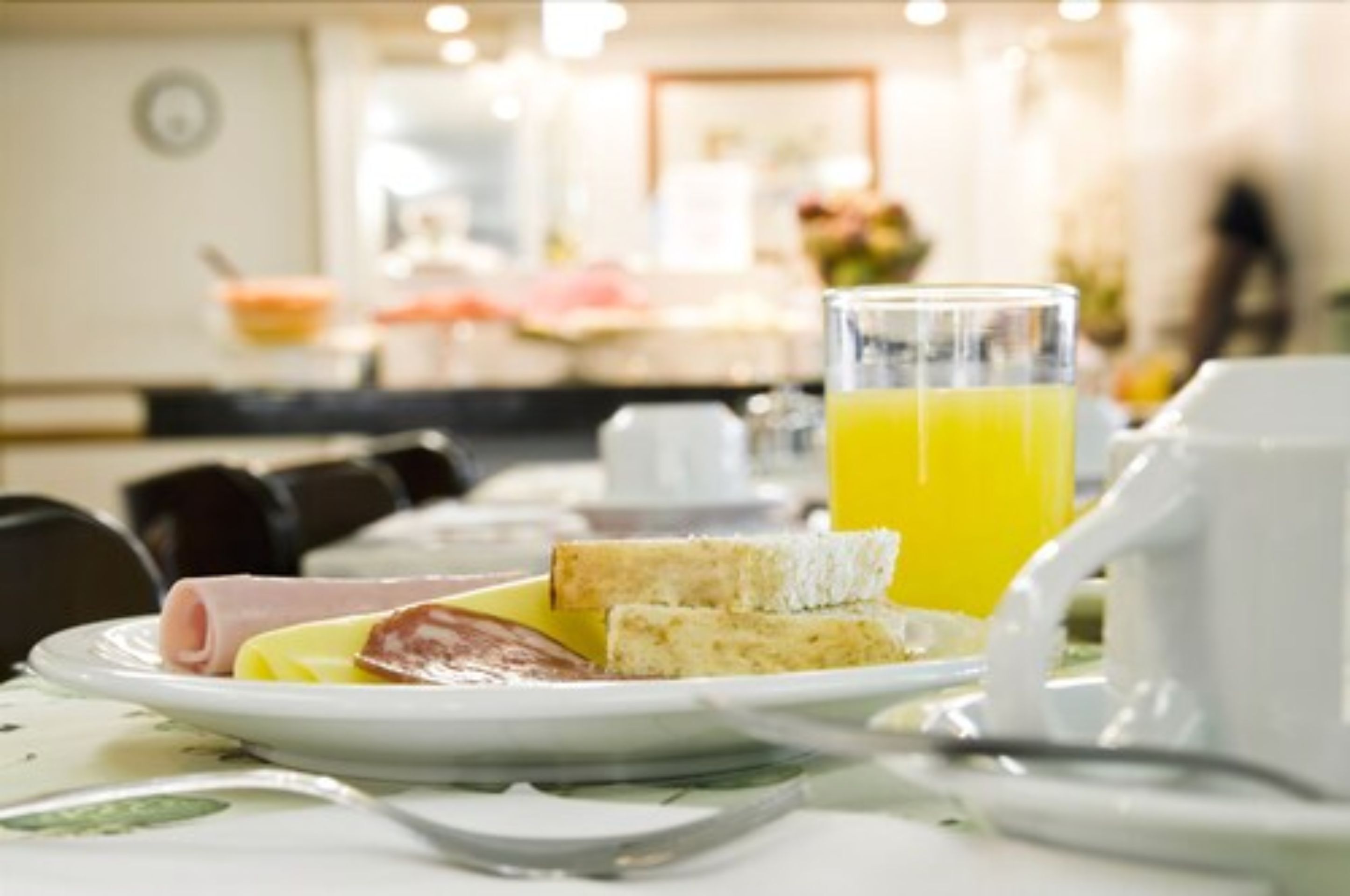 A breakfast setting with a plate of food, toast, and a glass of orange juice.