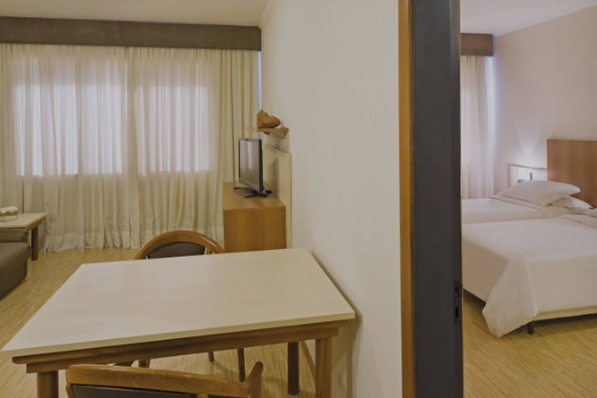A hotel room with a bed, a desk, a chair, a television, and curtains.