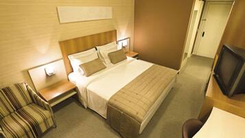 A hotel room with a bed, a TV, a chair, and a desk.