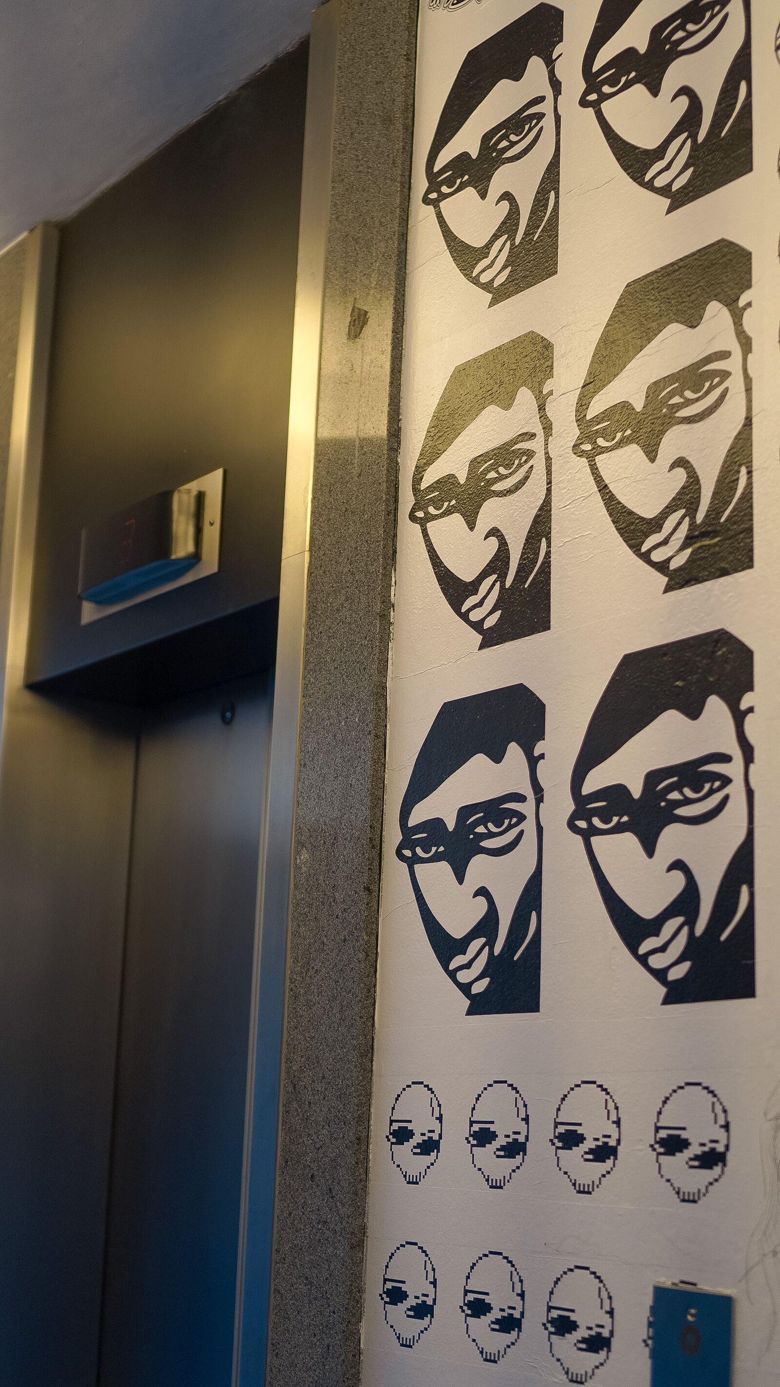A wall with multiple black and white stylized faces.
