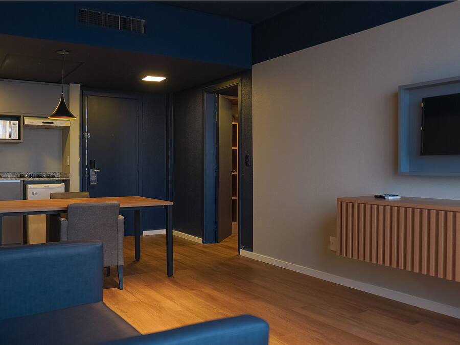 Ein modernes Wohnzimmer mit Essbereich, einer Küche und einem an der Wand befestigten Fernseher.