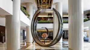 A modern lobby with a central sculpture, large columns, and a high ceiling. - Pullman Dubai Creek City Centre (Dubai)