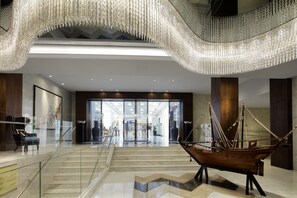 A spacious lobby with a grand chandelier, a model ship, and a modern staircase.