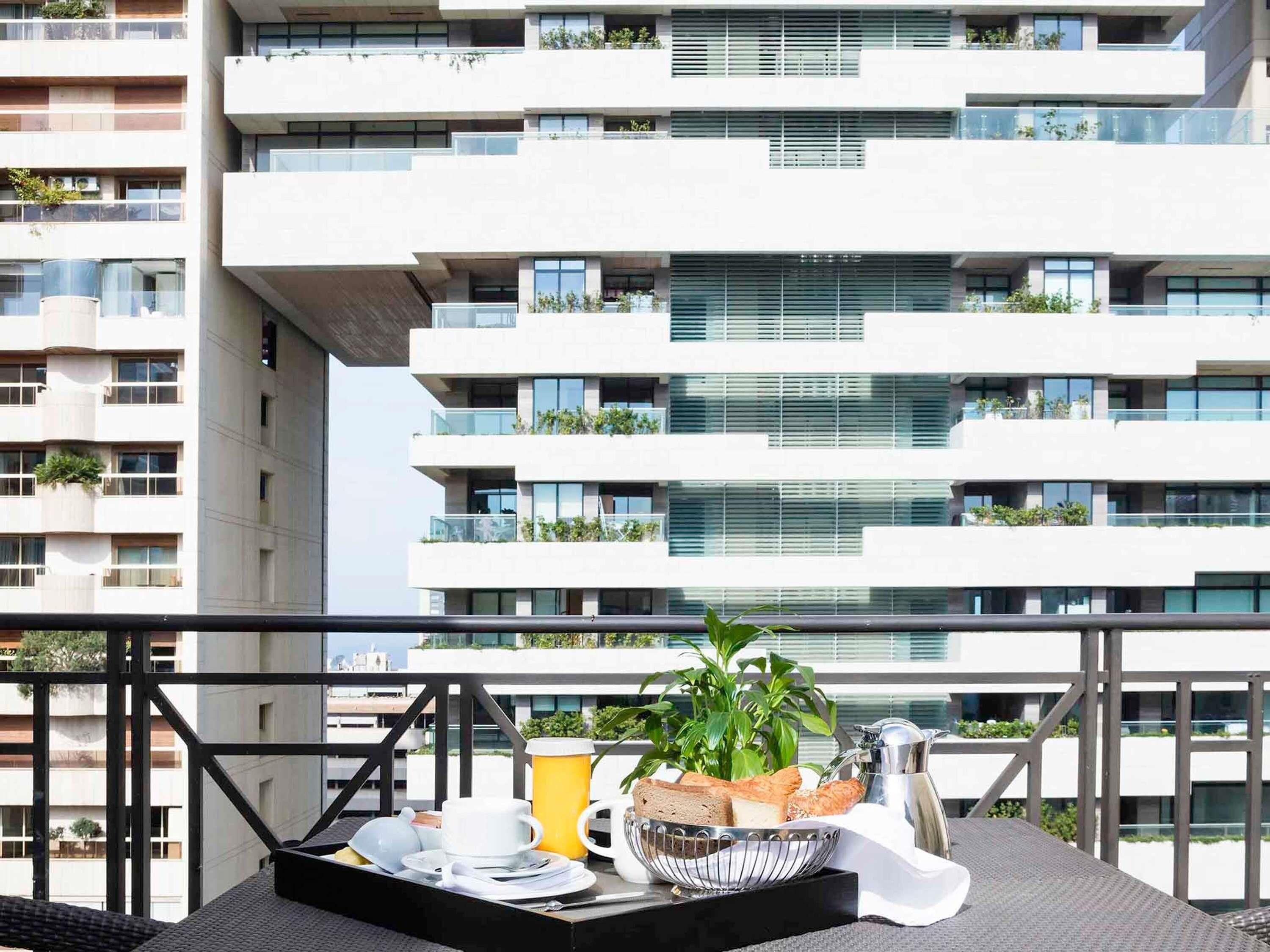 A balcony with a breakfast setup including a bowl of bread, a coffee pot, and a cup.