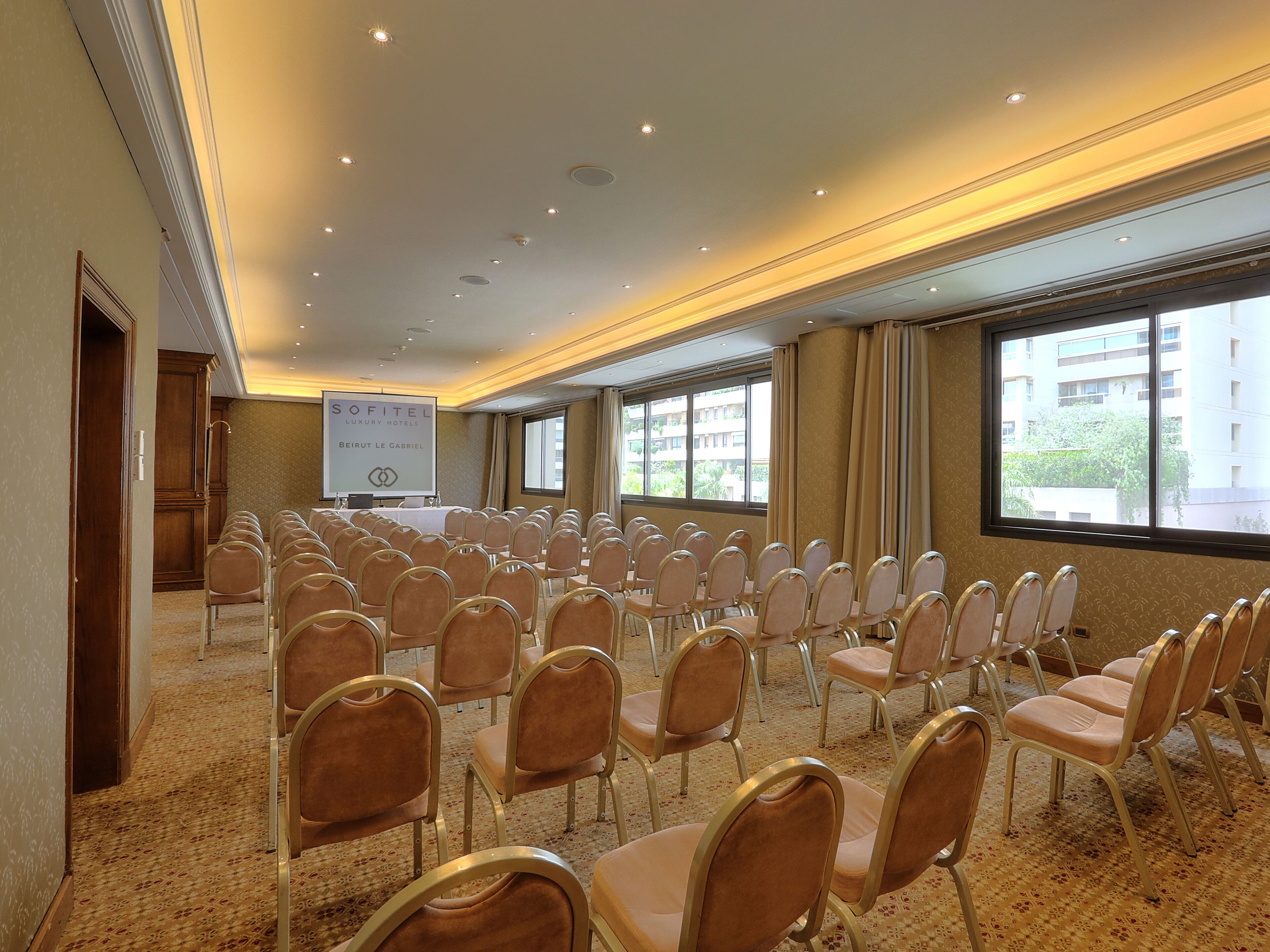 A conference room with rows of chairs, a podium, and a banner for Sofitel Beirut Le Gabriel.