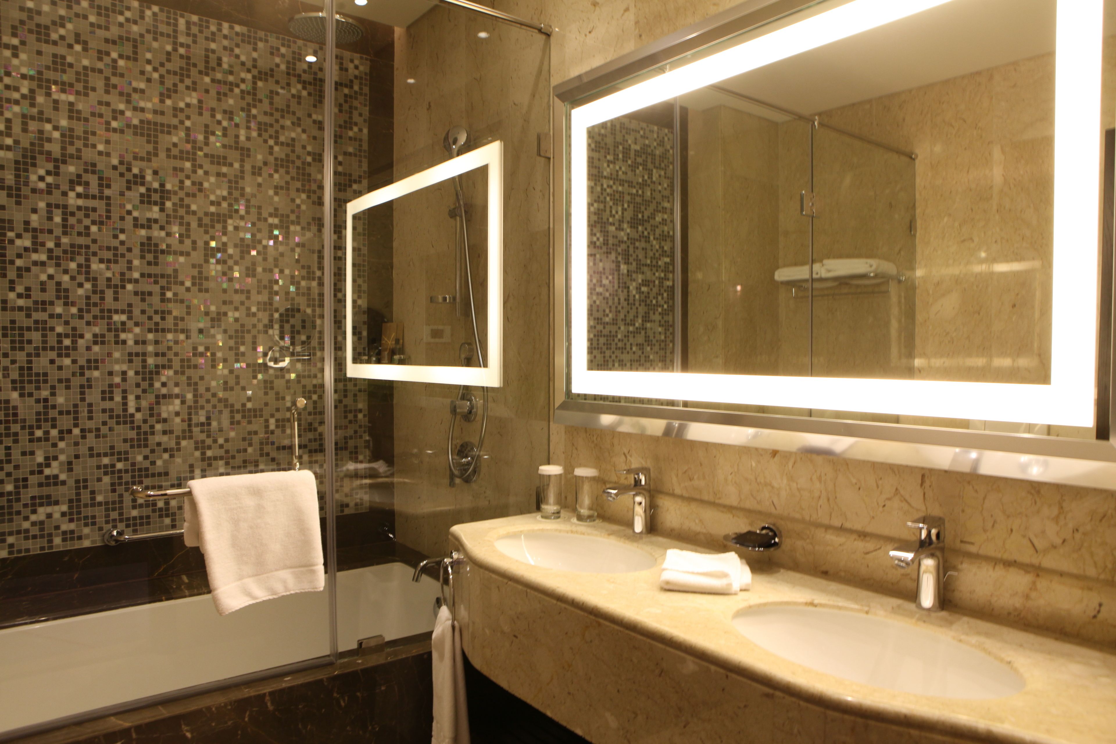 A bathroom with two sinks, a glass shower enclosure, and a large mirror.