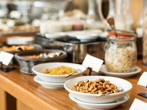Un bufé con diversos alimentos, incluyendo tazones de cereales y frutos secos.