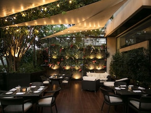 An outdoor dining area with tables and chairs, a wall of hanging plants, and a canopy overhead. - Sofitel Beirut Le Gabriel (Beirut)
